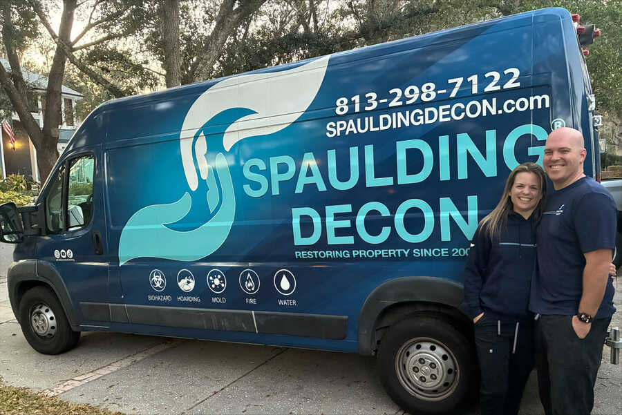 Katie Wilson and Kyle Wilson, owners of Spaulding Decon, standing in front of a branded Spaulding Decon van