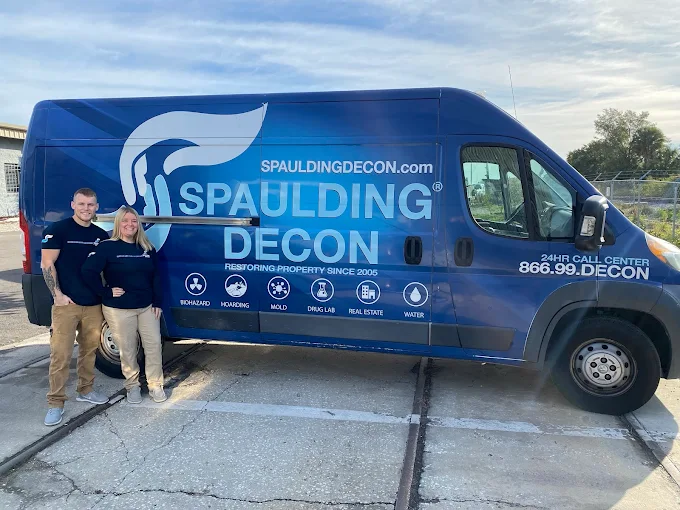 Andrew and Breanna Streacker standing next to a branded blue Spaulding Decon restoration van