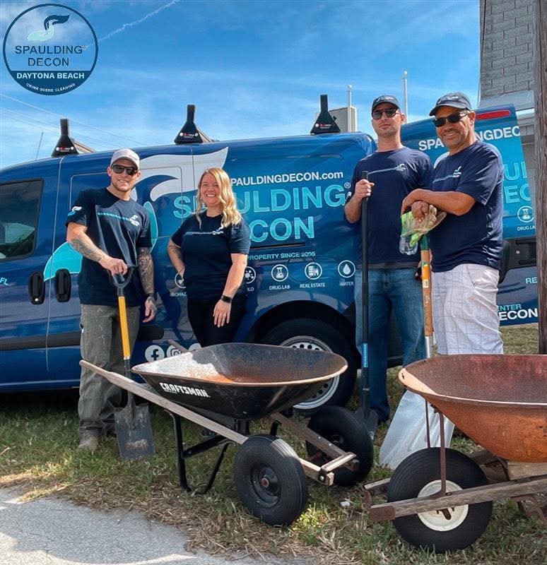 Spaulding Decon Daytona Beach restoration crew standing with wheelbarrows and shovels next to a branded company van