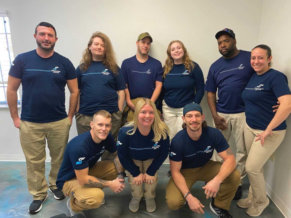 A group of nine Spaulding Decon team members wearing matching company uniforms posing for a photo